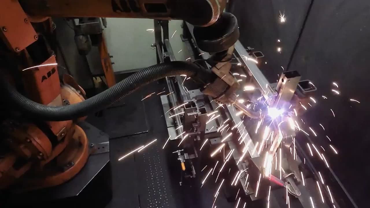 A robotic welder throwing sparks while producing a Tiger table component in Germany.
