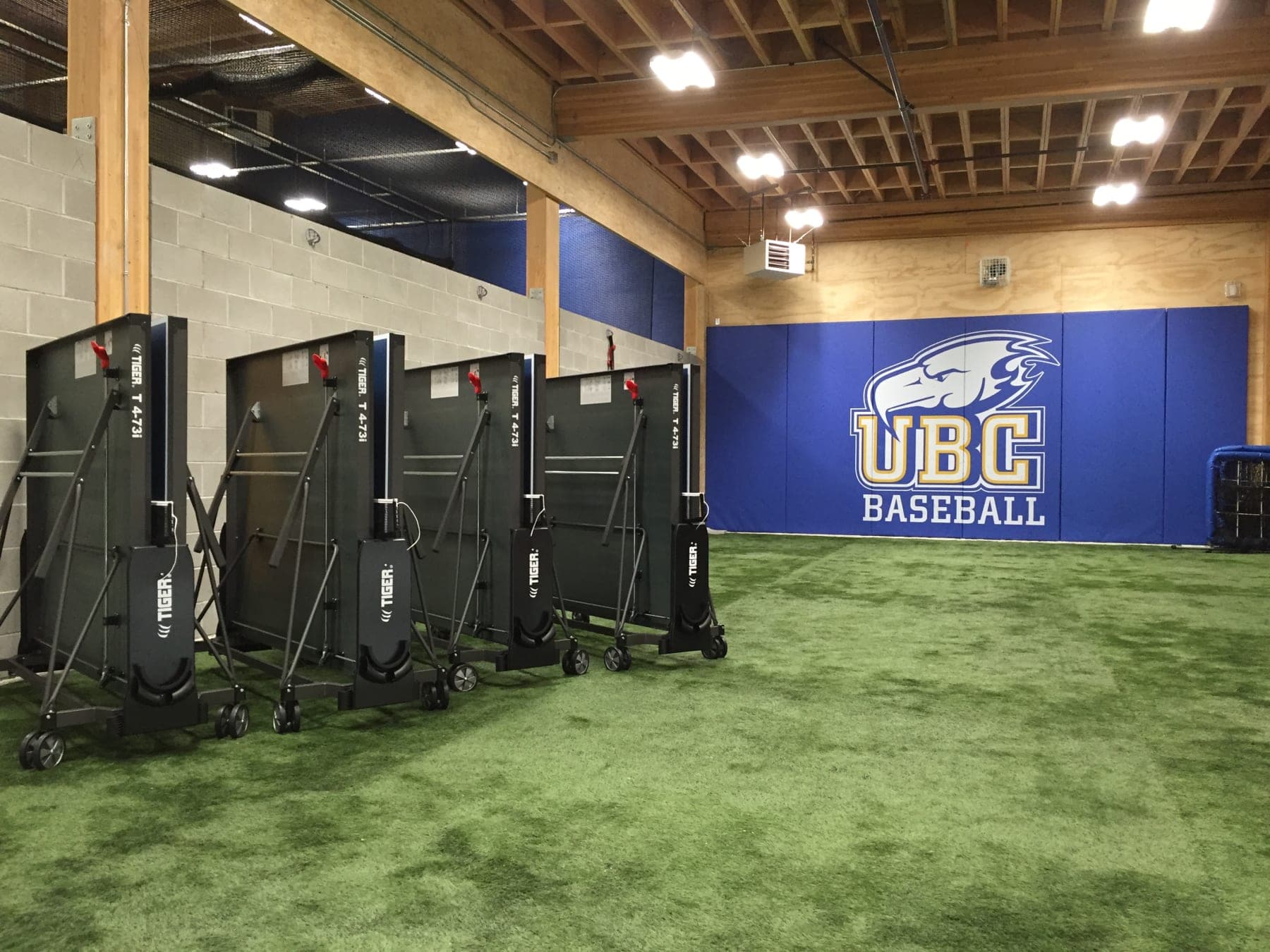 Five folded Tiger tables lined up inside UBC's baseball training facility.