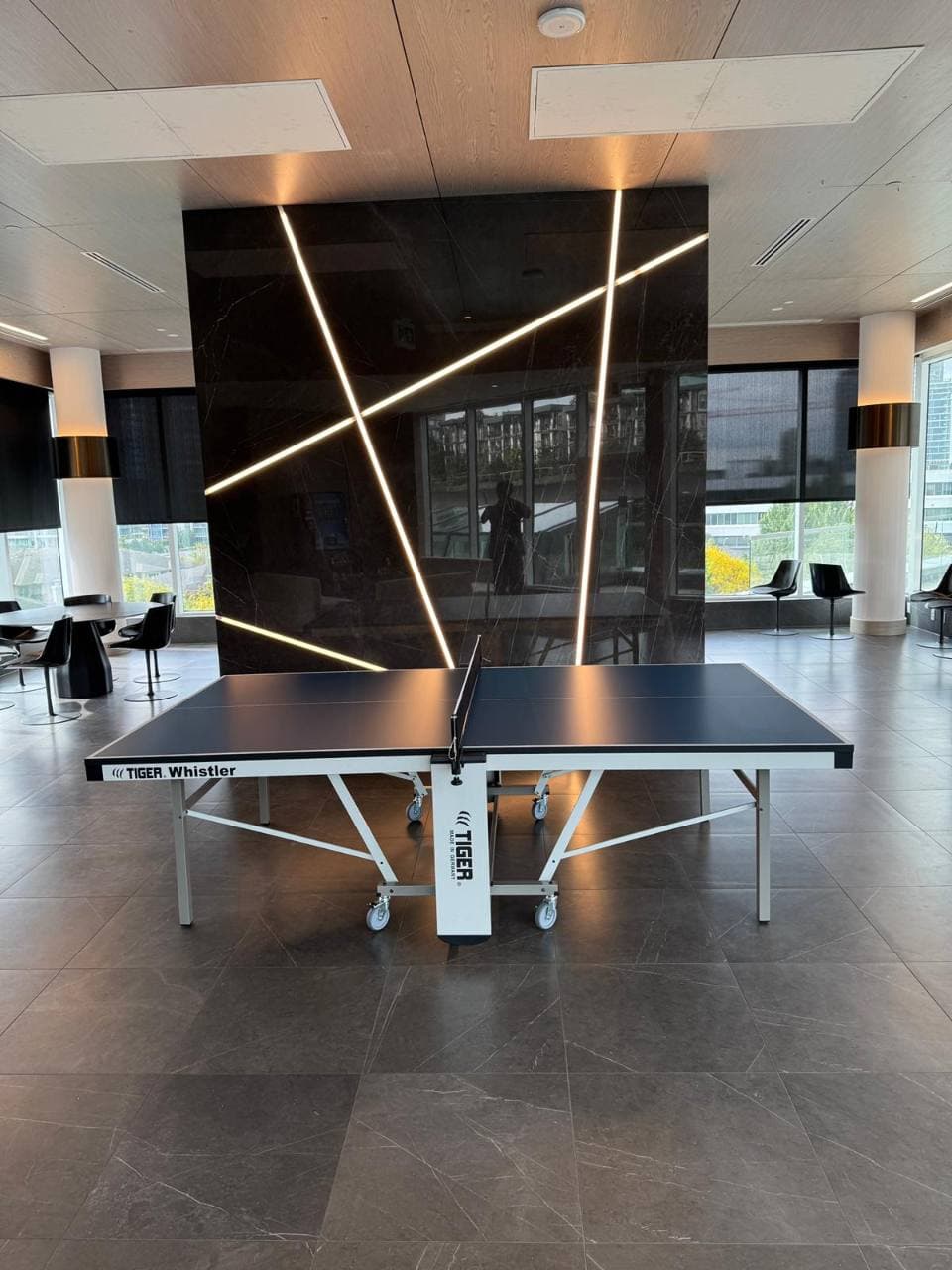Tiger Whistler Indoor PingPong table beneath geometric lights in a modern shared lobby.