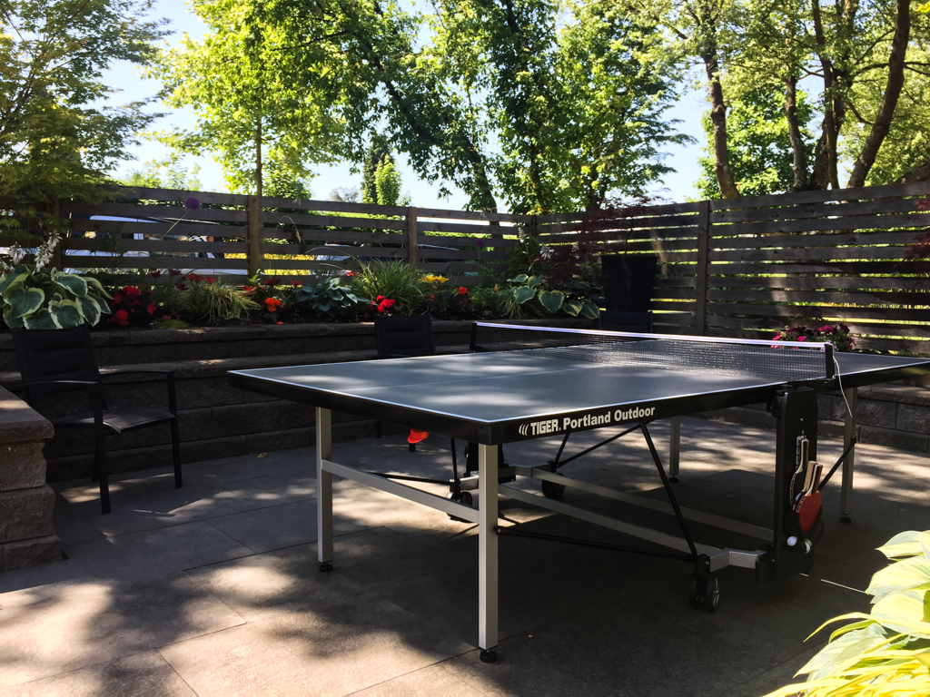A ping pong table in an outdoor setting with grass and trees in the background.