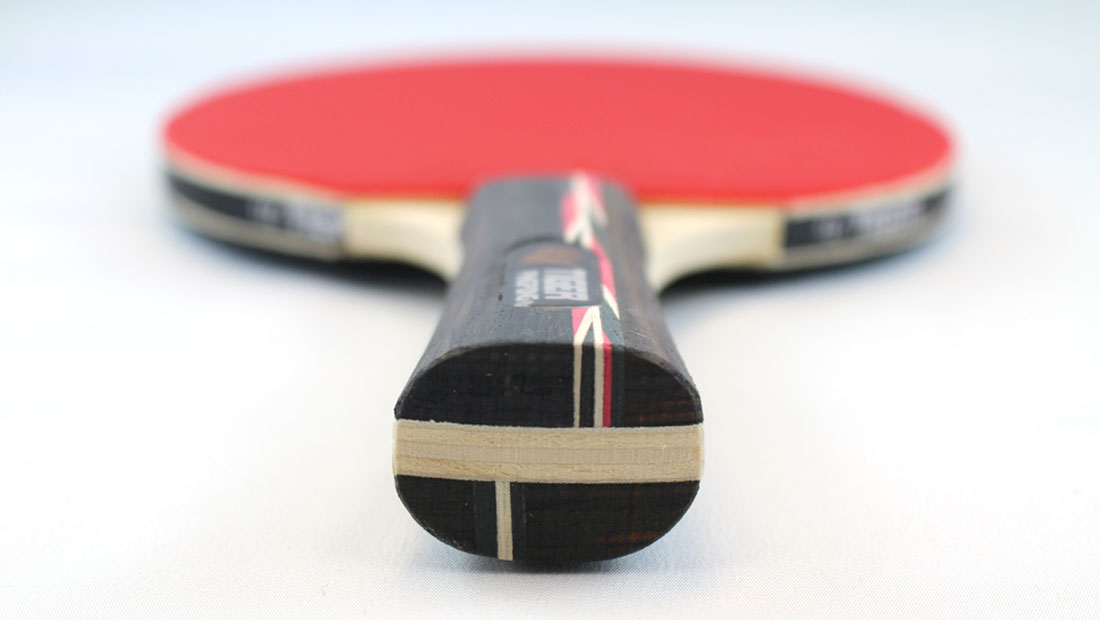 Red ping pong paddle on a white surface