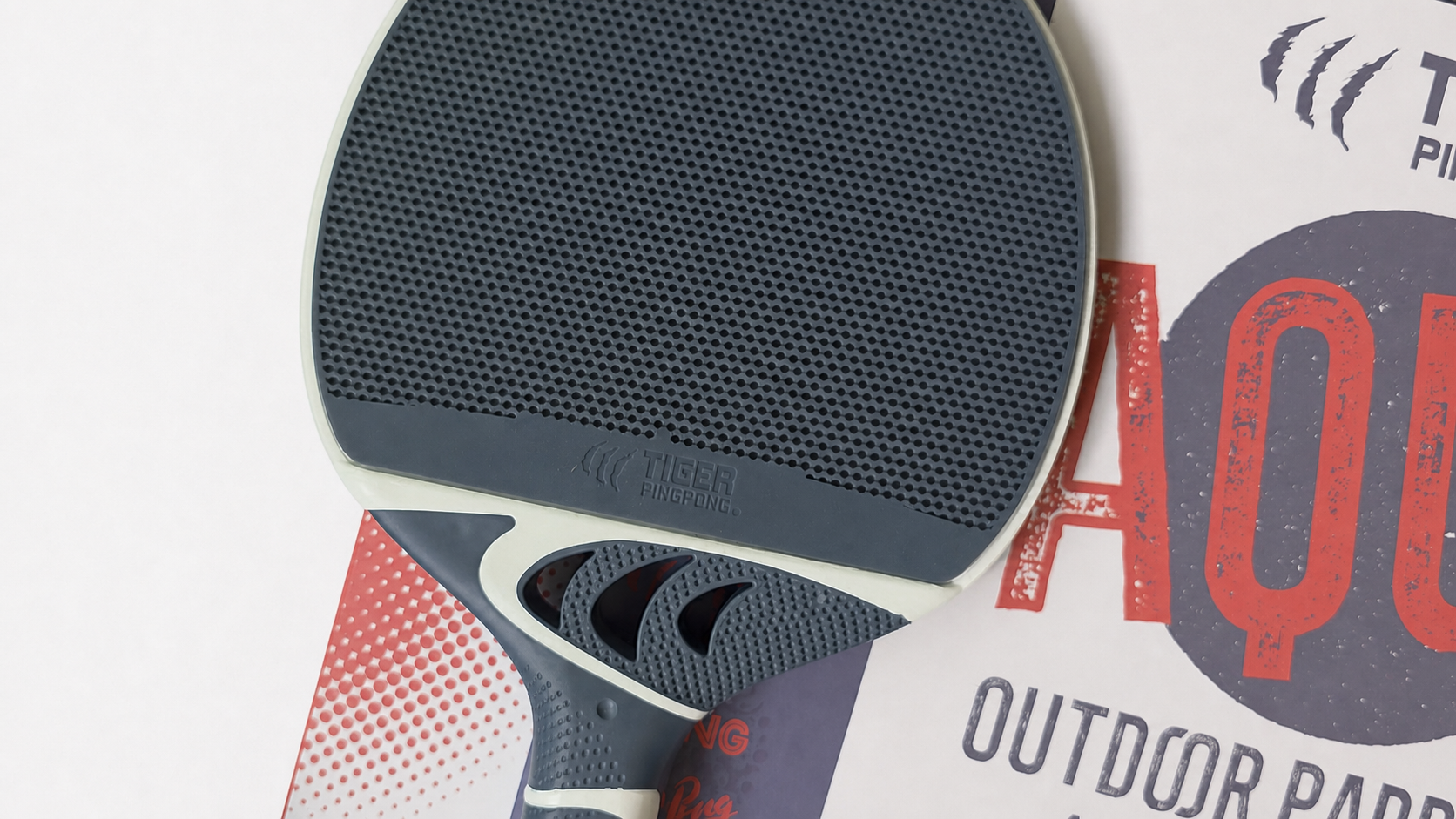 Close view of the Ocean Blue Aqua paddle face and grip beside its packaging.